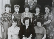 Лучшие работницы строче-вышивального производства в п.Мугреевский Бор (Стройка) на фоне знамени предприятия. 1980-е годы.